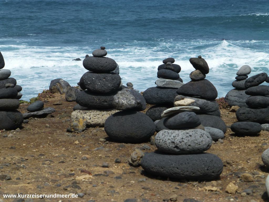 Schwarze Lavasteine als Grundlage für Steinmännchen auf Teneriffa. Direkt am Meer mit Blick auf den Atlantik